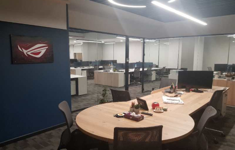ASUS Türkiye ofisi iç mimari tasarımı kapsamında, sistem departmanı yönetici alanında doğal ahşap masa, cam bölmeler ve modern LED aydınlatma